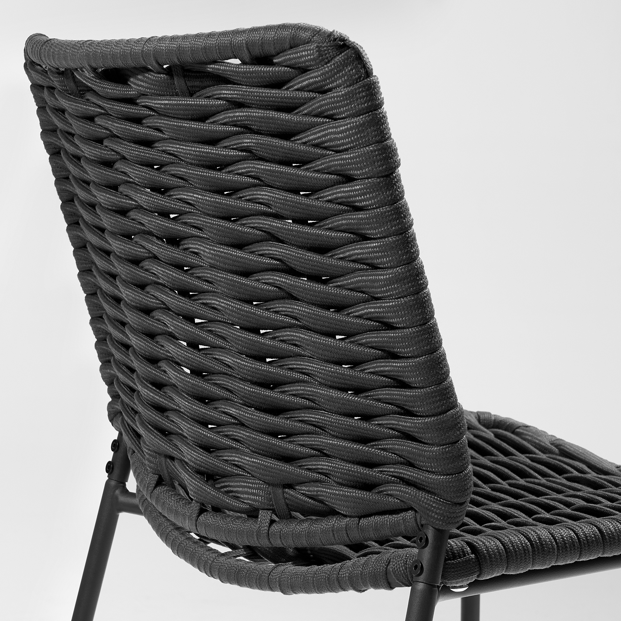 Schwarzer Outdoor-Stuhl aus Korbgeflecht mit geflochtenem Sitz und Rückenlehne, getragen von vier Metallbeinen.