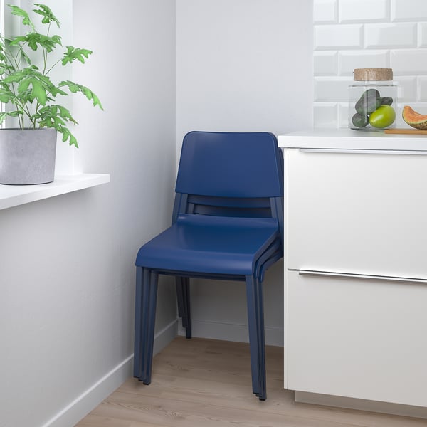 Blauer stapelbarer Stuhl, ideal zum Essen oder für den gelegentlichen Gebrauch, in der Nähe eines weißen Küchenschranks.