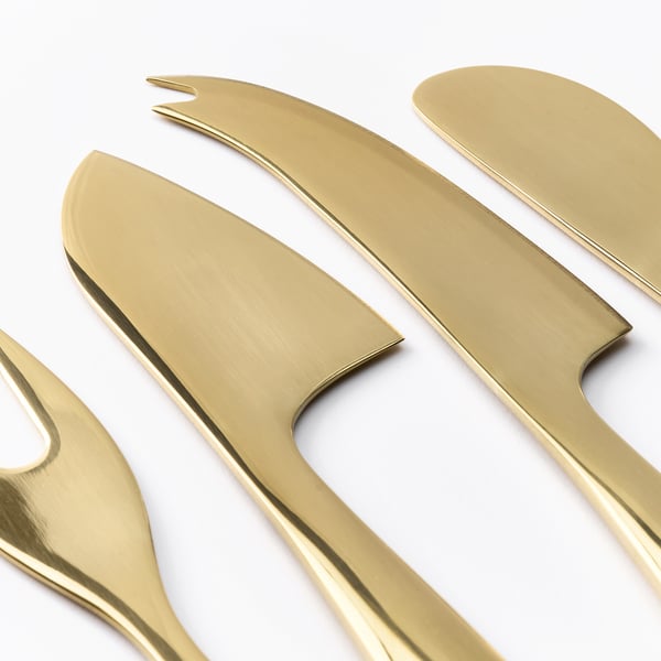 Sechs goldene Messer und Gabeln aus Metall, poliert und ordentlich auf weißer Oberfläche gelegt.