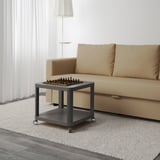 Kleiner, beweglicher Couchtisch mit Rädern, an dem ein Schachspiel befestigt ist, ideal für Mehrzweckräume.