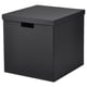 Eine TJENA Box in Schwarz. Es hat eine quadratische Form mit Deckel und Griffen und besteht aus recyceltem Karton.