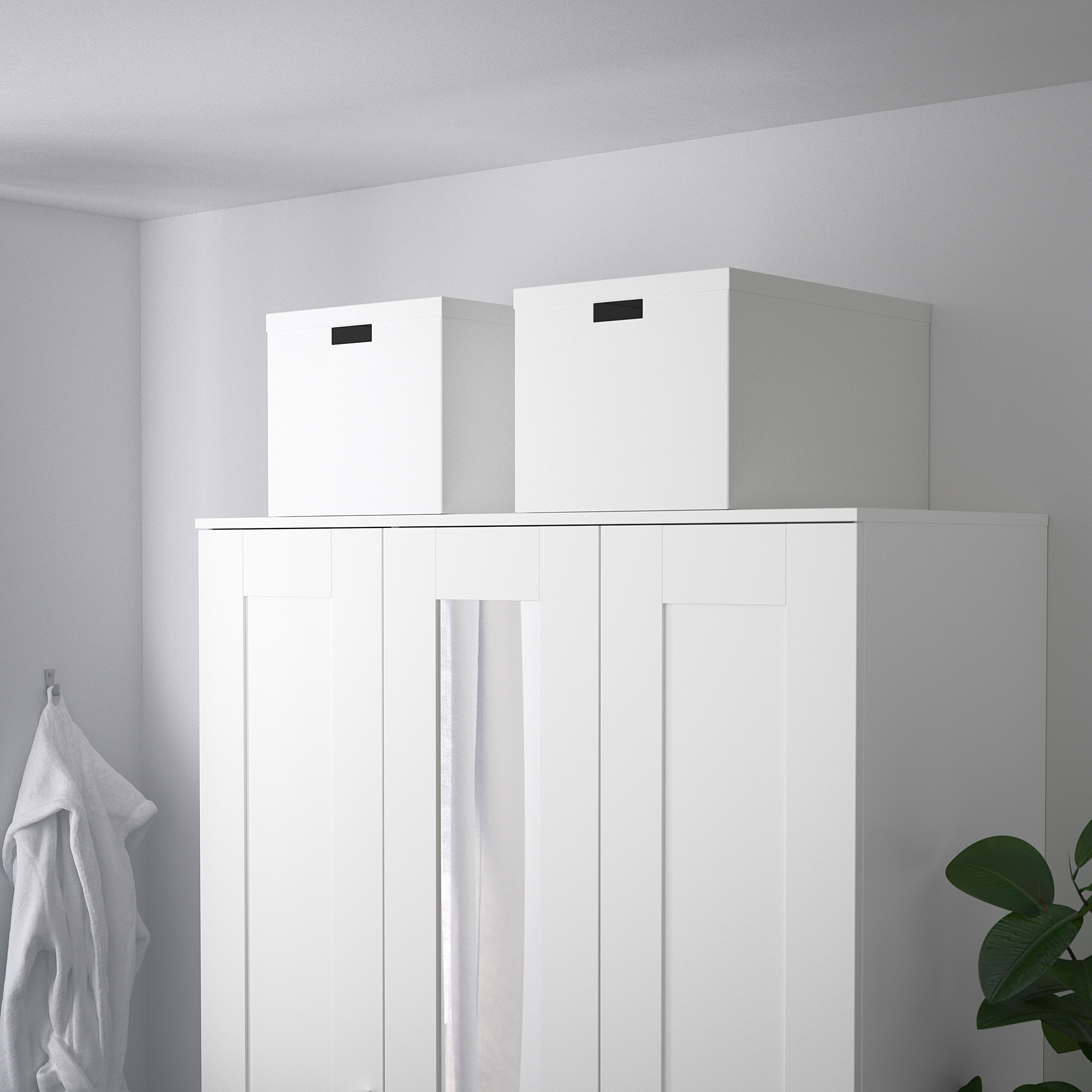 Zwei TJENA Aufbewahrungsboxen auf weißem Schrank, robust, recycelt, mit ausgeschnittenen Griffen.