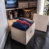 Organisierter Kleiderschrank mit gefalteter Kleidung in braunen TJOG-Boxen auf Holzboden.