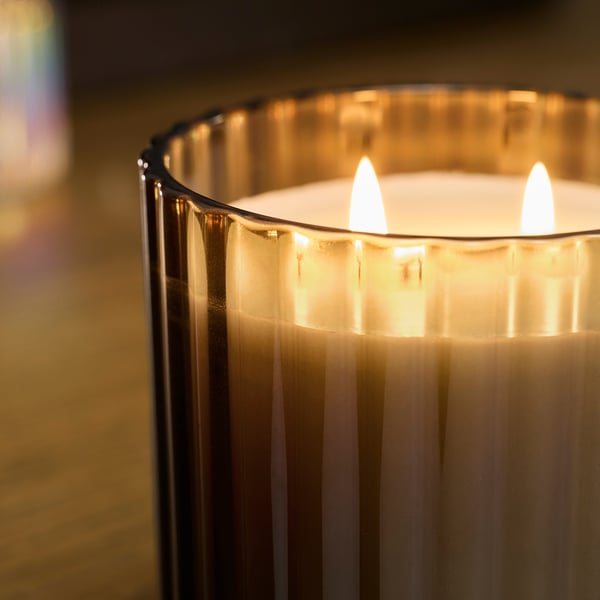 Brennende Dreidochtkerze in klarem Glas, die warmes, sanftes Leuchten ausstrahlte. Elegantes Design, gleichmäßiges Brennen, ruhige Atmosphäre.