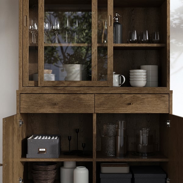 Holzschrank mit Glastüren, in denen Geschirr und Gläser ausgestellt sind. Hat Schubladen und Regale zur Aufbewahrung und Innenbeleuchtung vorbereitet.