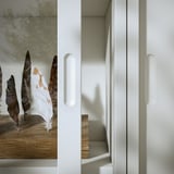 Minimalistischer cremefarbener Schrank mit Schiebetüren aus Spanplatten und Acrylfarbe, mit schlankem Design und integrierten Griffen.