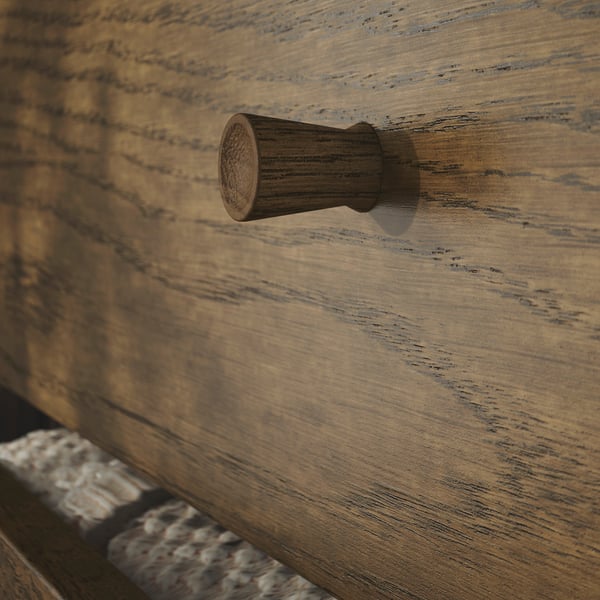Kleiner Schubladengriff aus Holz auf strukturierter, hellbrauner Holzoberfläche. Der Griff hat ein glattes, abgerundetes Design, was auf hochwertige Verarbeitung hinweist.