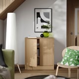 Holzschrank zwischen Lampe & Stuhl, mit Vase, Kerze, Büchern. Abstrakte Kunst darüber, leise Soft-Close-Regale, verstellbare Regale.
