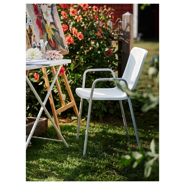 Modernes Ambiente im Freien mit weißem TORPARÖ-Stuhl und Tisch, Blumen auf dem Tisch.