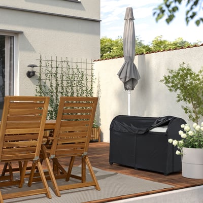 Stauraum im Garten: Holzstühle, grauer Teppich, Topfpflanze und überdachte Terrassenbox zum Organisieren von Kissen.