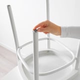 Eine Hand befestigt ein kleines, rundes, selbstklebendes Pad an einem Möbelbein und schützt so den Boden vor Kratzern.