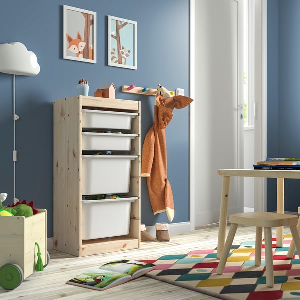 Kinderzimmer mit TROFAST hellem Kiefernschrank mit weißen Boxen. Heller Teppich, buntes Spielzeug und schlichtes Dekor.