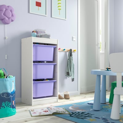 Kinderzimmer mit weißem TROFAST-Stauraum, lila Behältern und Spielzeugtisch. Buntes Dekor, Teppich und Spielzeug.