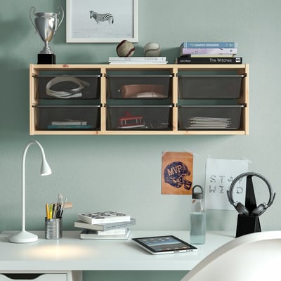 TROFAST Wandaufbewahrung mit Netzboxen über dem Schreibtisch, in denen verschiedene Gegenstände Platz finden. Lampe, Tablet und Wasserflasche auf dem Schreibtisch darunter.