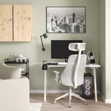 Minimalistisches Homeoffice: weißer Gaming-Stuhl, kompakter Schreibtisch, schwarzer Monitor, Stadtbildfoto.
