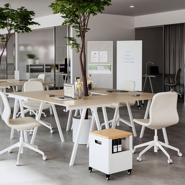 Moderne Büroeinrichtung mit einem beigen TROTTEN-Schreibtisch, weißen Stühlen und einem Baum. Sauber und organisiert mit eingebauten Tischhaken.