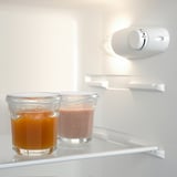 Zwei Gläser im Kühlschrank: eines mit Orangensaft, eines mit Erdbeer-Smoothie, für die Frische aufbewahrt.
