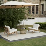 TVARÖ Outdoor-Set: beige gepolsterte Stühle und Couchtisch aus Korbgeflecht unter einem großen cremefarbenen Sonnenschirm auf einer gefliesten Terrasse.