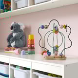Buntes UPPSTÅ Holzspielzeug mit beweglichen Blättern und Blumen. Neben Koala & Blöcken im Regal.