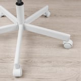 Weißes Bürostuhlgestell mit fünf Rollen auf hellem Holzboden, das sich durch robustes Design und Mobilität auszeichnet.