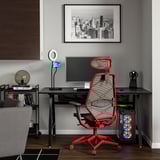 Modernes Homeoffice mit rotem Gaming-Stuhl, Schreibtisch, Monitor, Tastatur und Ringlicht unter Stadtbildrahmen.