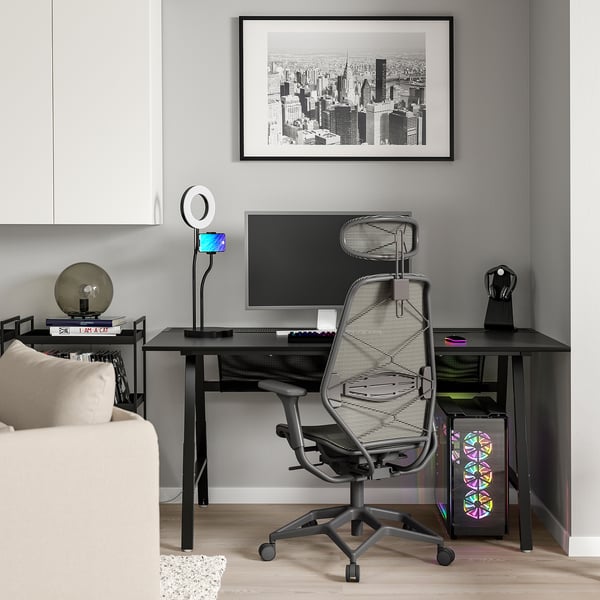 Ein modernes Home-Office-Setup mit einem schwarzen UTESPELARE-Gaming-Schreibtisch mit Netzrückenlehne, LED-Licht, Monitor und Computerturm.