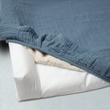 Eine Wickelauflage mit einem weichen, wendbaren Bezug aus Bio-Baumwolle in Blau und Beige mit einer kleinen bestickten Katze.