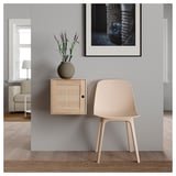 Modernes Zimmer mit Holzschrank, getrockneten Pflanzen, Stuhl, Teppich und Bild.