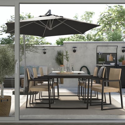 Modernes Esszimmer im Freien mit schwarzem Tisch und Stühlen unter einem großen Sonnenschirm. Perfekt für den Einsatz auf der Terrasse.