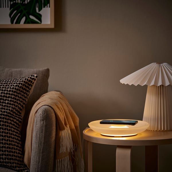 Dunkler Raum mit weißem Ladegerät, Lampe und Stuhl mit Vorhängen.