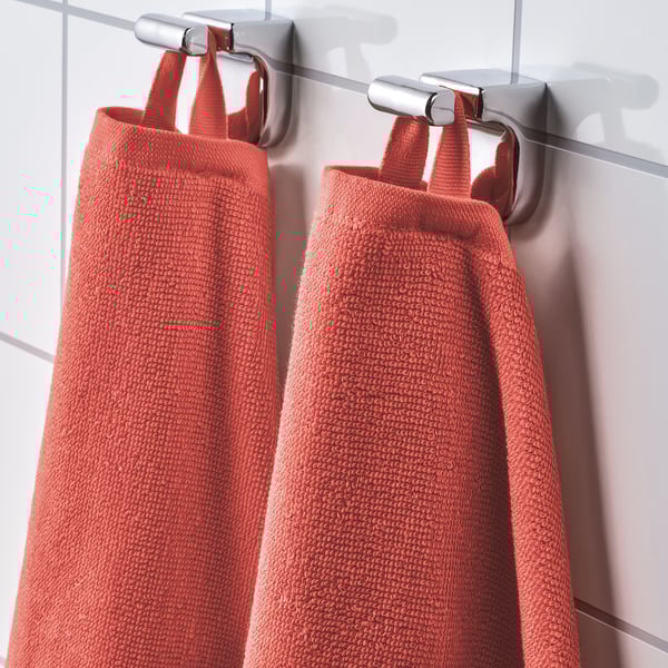 Zwei leuchtend rote Handtücher hängen ordentlich an silbernen Haken und zeigen ihre weiche, saugfähige Textur und leuchtende Farbe, ideal für den Gebrauch im Badezimmer.