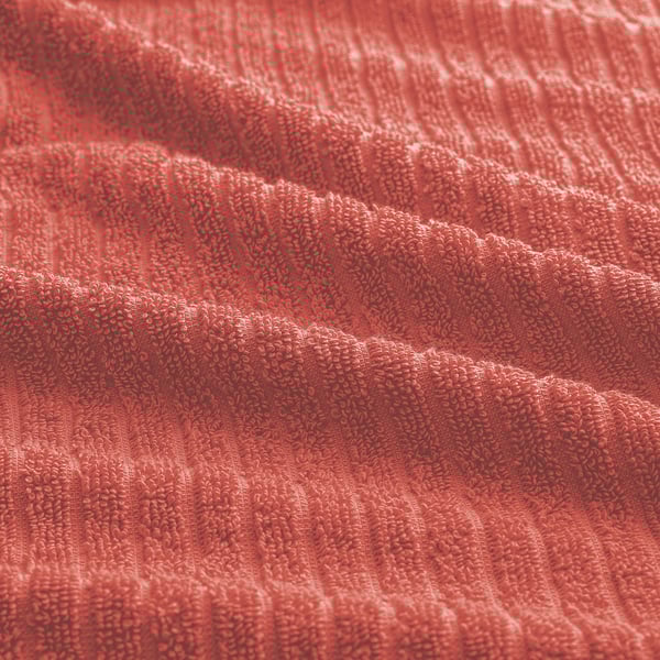 Lebendiges, weiches und strukturiertes rotes Handtuch; Frottee mit absorbierender Qualität, dargestellt in einem wellenförmigen Muster.