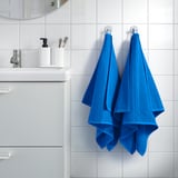 Blaue VÅGSJÖN Handtücher hängen an Wandhaken neben weißem Waschbecken und Spiegel.