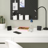Schreibtisch mit Lampe, Notizen, Notizbuch, Telefon, Lautsprecher, Stuhl, Kaktus.