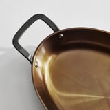 Glänzender, gut verarbeiteter Bräter aus Kohlenstoffstahl mit robusten Griffen, bereit für gleichmäßiges Garen bei Hitze.
