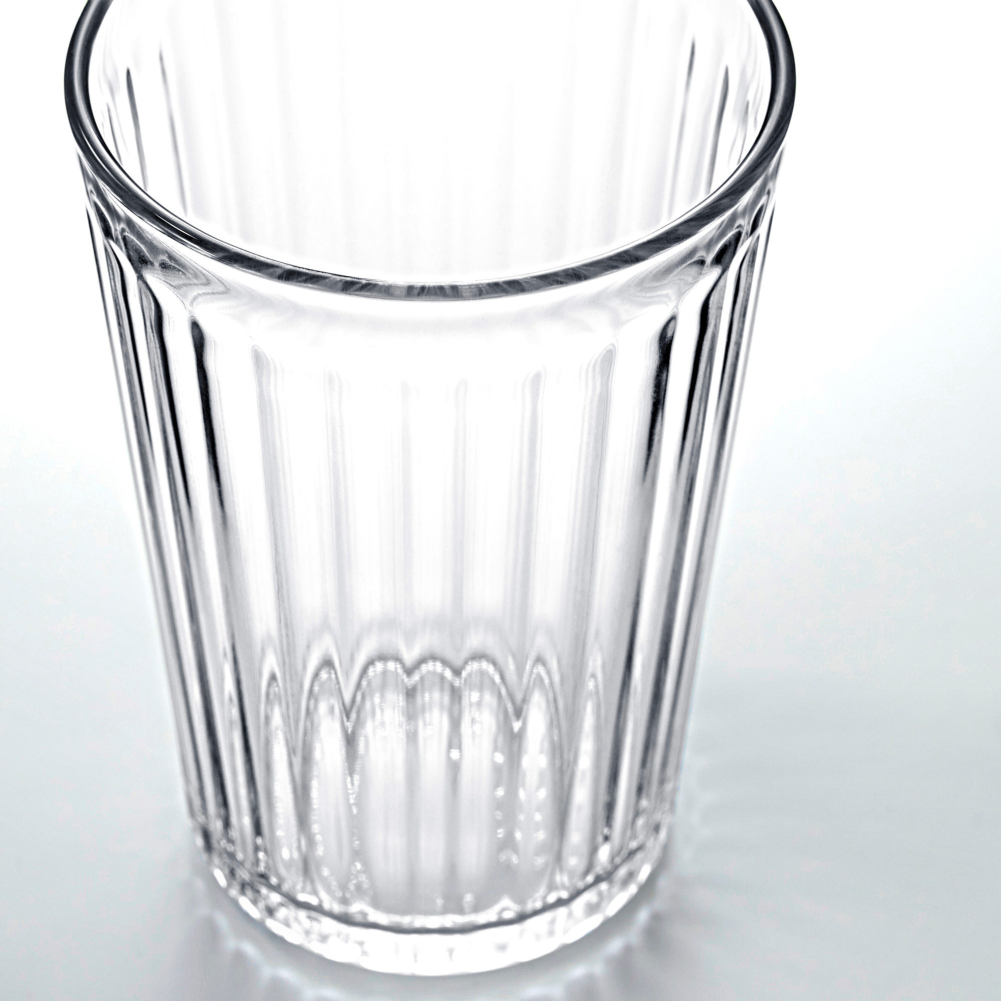 Klarer, kannelierter Glasbecher aufrecht abgebildet, leer. Einfaches Design, langlebig, transparent und elegant.