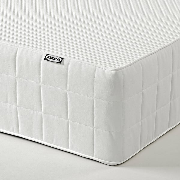 IKEA-Matratzeneckdetail mit Steppmuster und weißem Etikett mit Logo.