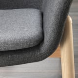 Dunkelgrauer Polsterstuhl mit geschwungener Rückenlehne und Holzbeinen, die die Qualität des Stoffes und des Designs hervorheben.