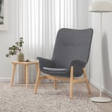 Modernes Wohnzimmer mit grauem VEDBO-Sessel, Beistelltisch aus Holz und Stehlampe.