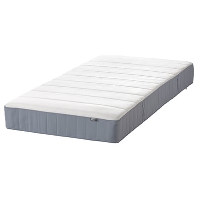 Eine IKEA VESTERÖY Matratze, weiß mit grauen Seiten, rechteckig. Es bietet einen mittelfesten Komfort mit einzelnen Taschenfedern und einer Schaumstoffschicht.