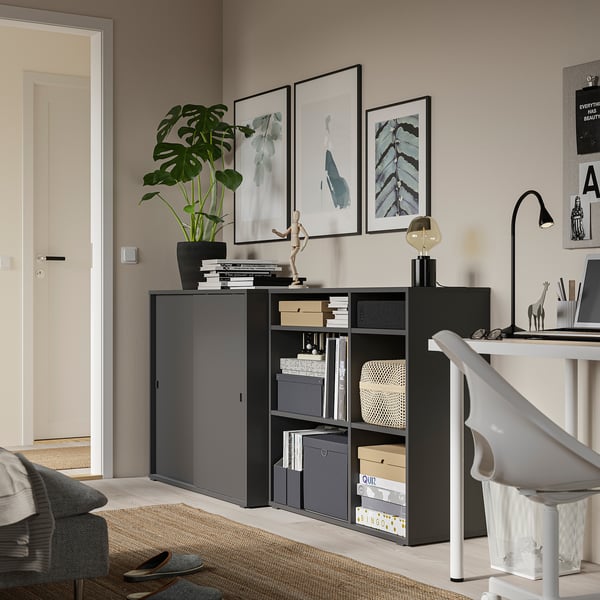 Homeoffice mit schwarzem Schrank, Schreibtisch, Pflanzen und Kunst.