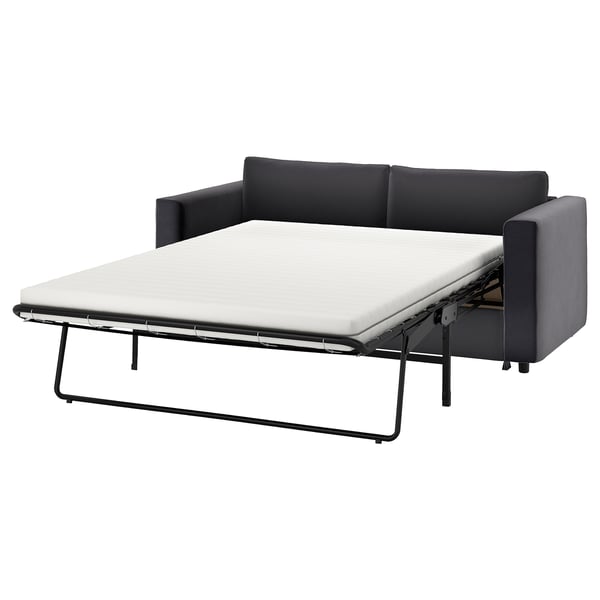 Ein schwarz-graues VIMLE-Schlafsofa mit einer ausziehbaren weißen Matratze. Es hat ein modernes Design mit klaren Linien und stützenden Kissen.
