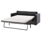 Ein schwarz-graues VIMLE-Schlafsofa mit einer ausziehbaren weißen Matratze. Es hat ein modernes Design mit klaren Linien und stützenden Kissen.