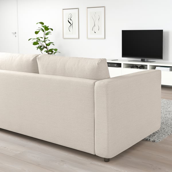 Modernes Wohnzimmer mit beigem VIMLE-Schlafsofa, Flachbildfernseher, minimalistischer Kunst und Pflanzen.