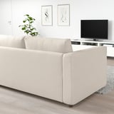 Modernes Wohnzimmer mit beigem VIMLE-Schlafsofa, Flachbildfernseher, minimalistischer Kunst und Pflanzen.