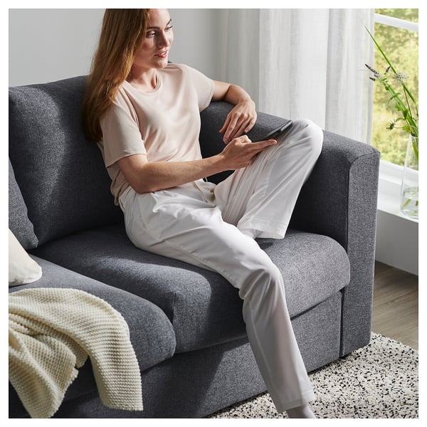 Person auf grauem VIMLE-Schlafsofa mit klaren Linien und dicken Kissen.