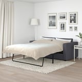 Modernes Schlafzimmer mit dunkelgrauem VIMLE Schlafsofa, Teppich, Lampe, Pflanze, Vorhängen, Holzböden.