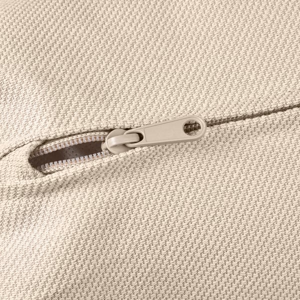 Reißverschlussdetail auf einem beigefarbenen, strukturierten Stoff, der auf eine hochwertige Verarbeitung hindeutet.