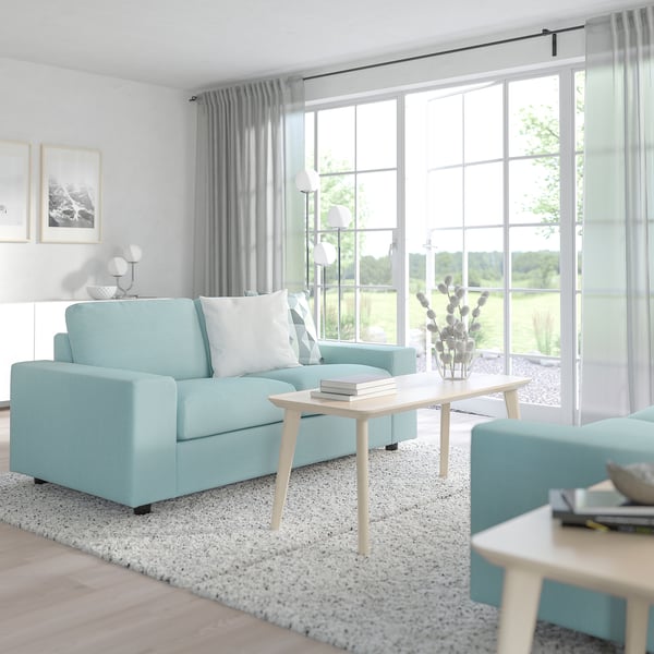 Modernes blaues VIMLE-Sofa in ruhigem Wohnzimmer, Couchtisch in der Mitte, große Fenster.