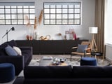 Modernes Wohnzimmer: dunkelgraues VIMLE-Sofa, gemusterter Teppich, Couchtisch mit Tassen, schwarze Konsole, Korbstuhl, große Fenster.